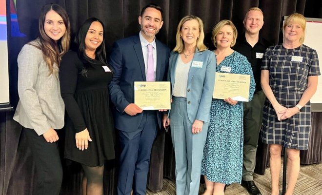 Seven professionals standing side by side holding certificates