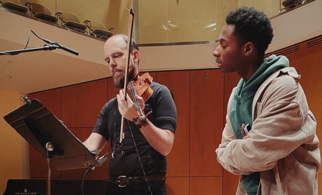 Composition student on stage with professor with violin