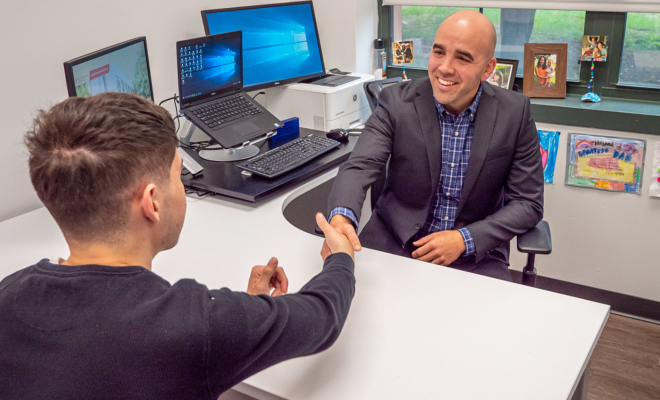 Student shaking hands with his academic advisor during an advising appointment.