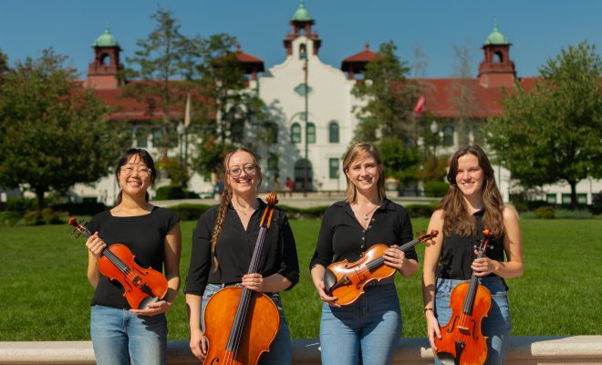 String Quartet standing in front of Susan Cole Hall at Montclair State University