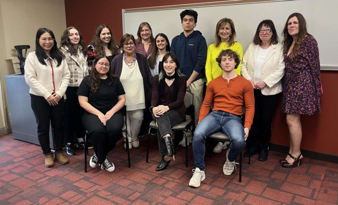A group of people pose together in front of a whiteboard in a classroom