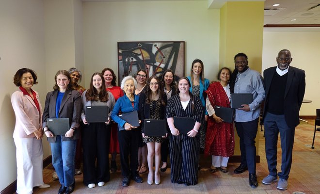 A group of college students and faculty pose together, the students are holding certificates