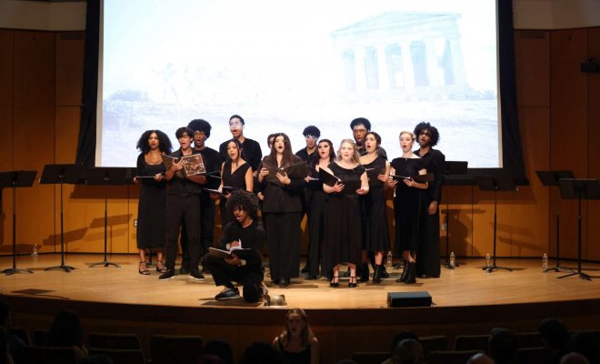 Group of college students singing together on stage during a choir performance