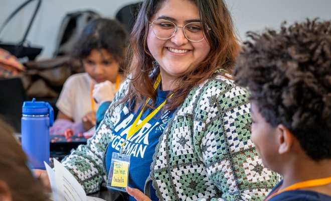 Female os smiling talking to a child with glasses on.