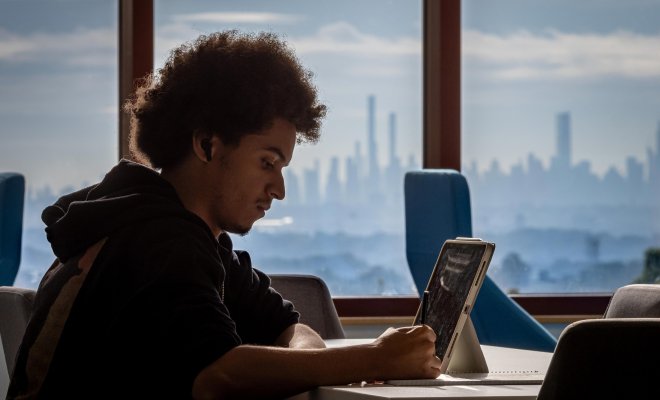 Student working online with NYC skyline in background