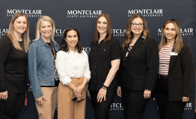 Student Success Team pose in front of a step and repeat.