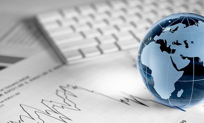 stock photo of glass globe on top of papers with line graphs and a computer keyboard in the background