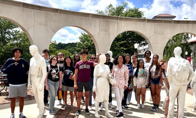 A group of people pose outdoors with an art installation