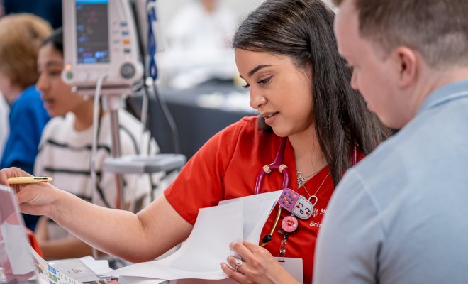 Nursing student in scrubs reviewing medical report with a university staff member.