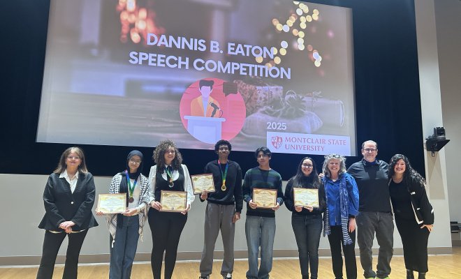 Speech competition winners holding their certificates on stage, smiling.
