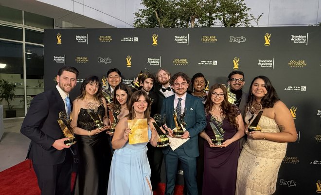 Students pose for a photo with Emmy awards on the red carpet.