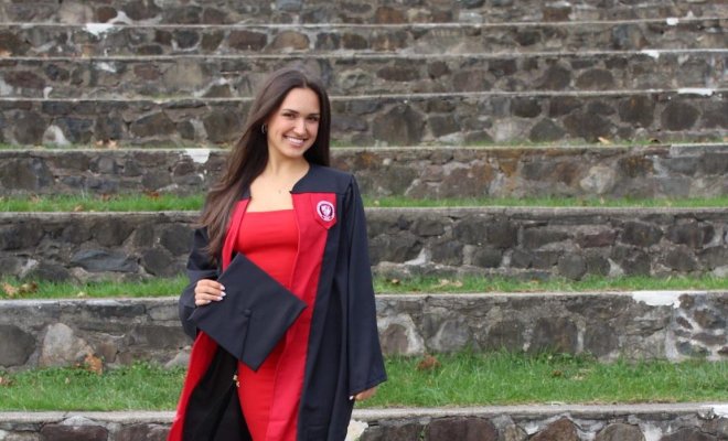 Alum Claudia Challender posing in graduation gown.