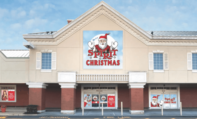 A brown and white two-story building with signs promoting a Christmas store.