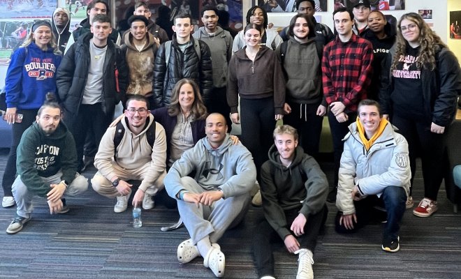 Students in two rows, some sitting and others standing, smiling and looking relaxed.