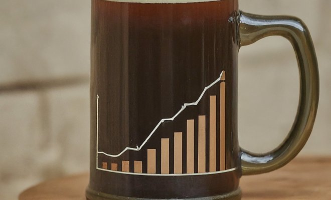 A mug of dark beer with foam on top with a line graph on the mug.