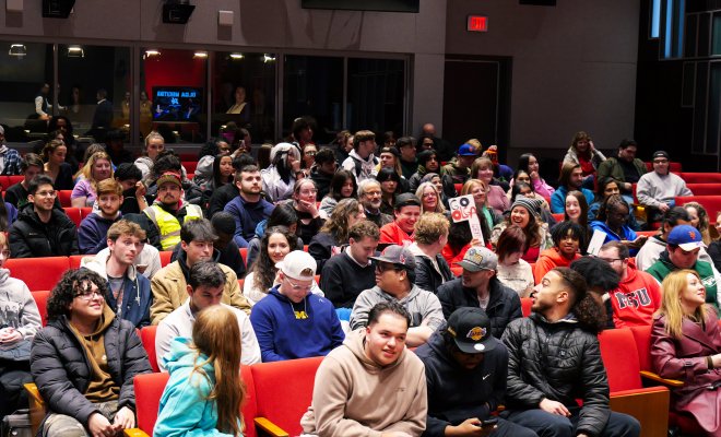 Students in auditorium seats conversing.