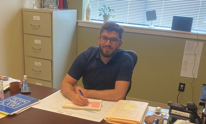 a man sits behind a desk in an office and writes into a notebook