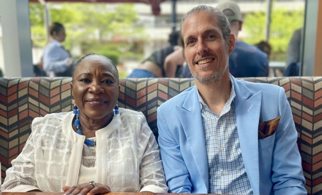 Two people sit side-by-side in a booth in a dining room