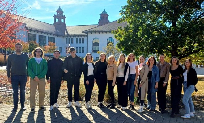 A group of people pose in a line outdoors in the fall