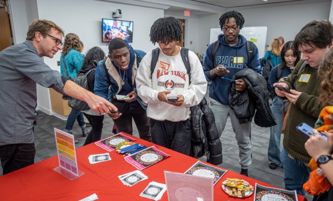 A group of college students stand at a table at a career fair and speak with a representative