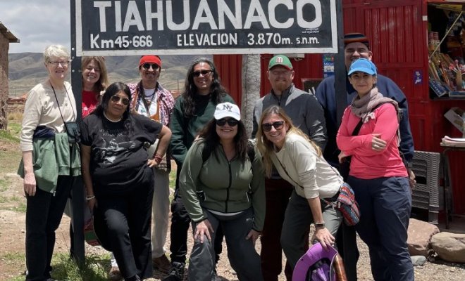 A group of people pose in front of a sign for Tiahuanaco