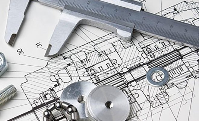 design plans on a table with nuts, bolts, washers and a caliper