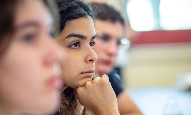 A close up of a seated student focusing on the professor 