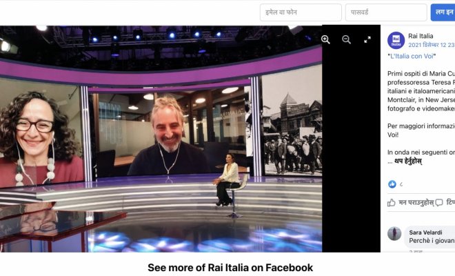 A woman sits in a tv studio and speaks with interviewees on two large video boards