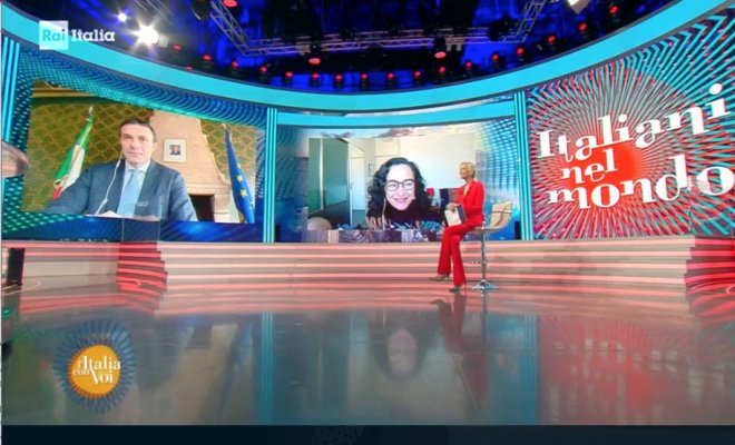 Interior of a television studio with people sitting with large video boards in the background