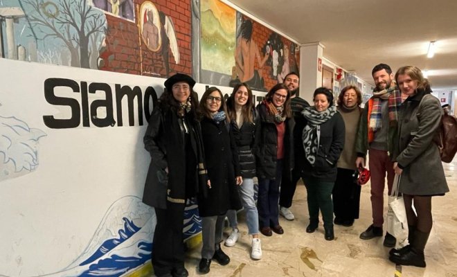 A group of people wearing winter coats pose in a building lobby