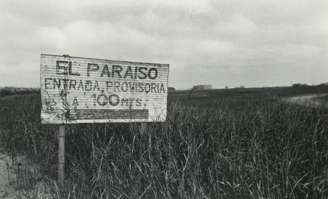 A black and white image of a metal sign in the middle of a farm field