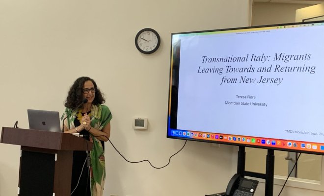 A woman stands at a podium and delivers a presentation