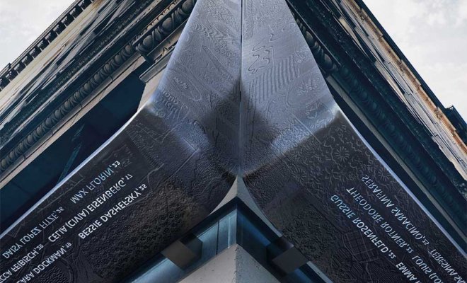 Curved metal memorial with engraved text mounted on the corner of a historic building