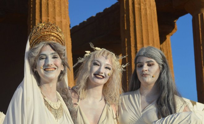 Three women dressed in classical-era Greek togas 