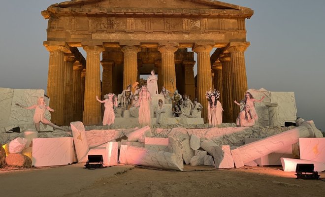 A stage with fake white marble pieces and a Pathenon backdrop