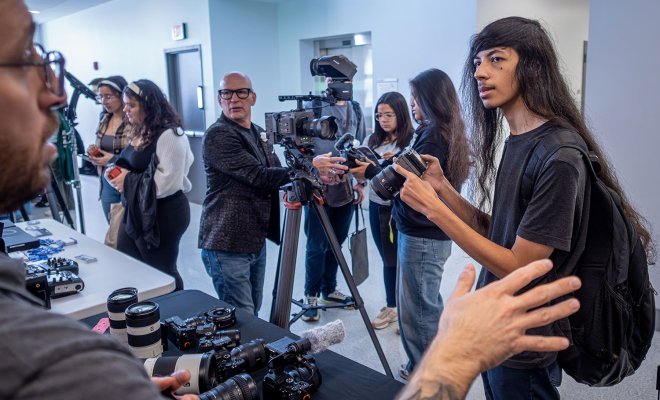 Student checking out a camera as a professional explains its features.