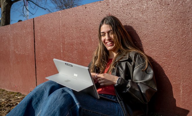 student working on laptop smiling
