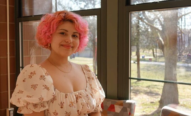A woman poses for a headshot by a sunny window