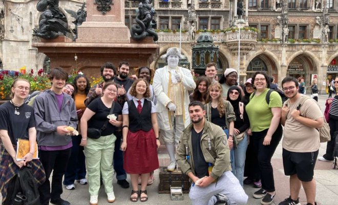 A group of college students pose with a human statue on the streets of Marienplatz in Munich