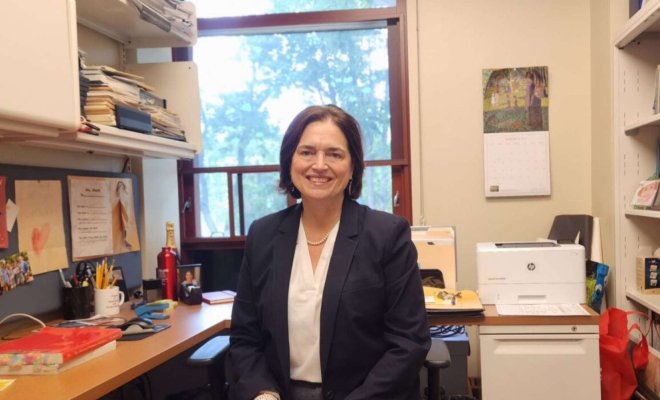 A woman poses at a desk in an office