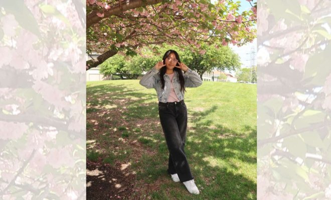 A woman poses beneath a cherry blossom tree.