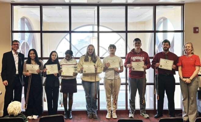 A group of college students stand in a line holding paper certificates