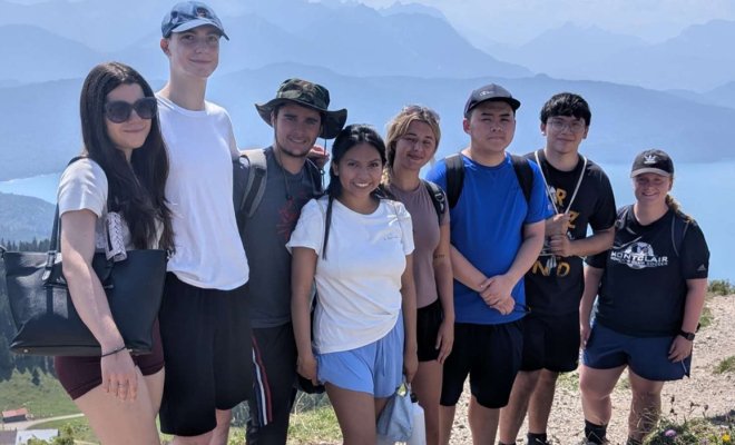 A group of college students pose on a peak in the German Alps