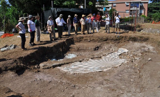 Archaeologists examine the remains of a patterned mosaic floor at an excavation site