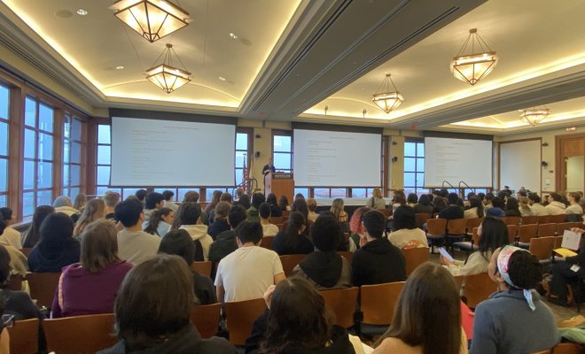 A large auditorium filled with people watching a presentation