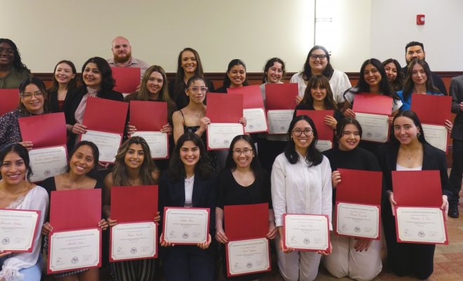 A group of people pose together each holding a certificate inside a holder