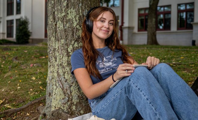 Student studies outdoors on campus.