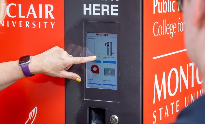 A hand points to a digital keypad on the Harm Reduction Kiosk.