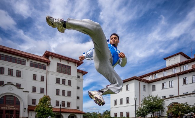 Cameron Massay demonstrates a kick used in Taekwondo on a college campus.