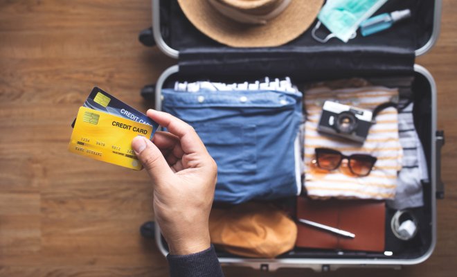 Person holding credit cards over a suitcase 